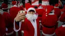 Seorang pria berpakaian sebagai Santa Claus berselfie selama acara amal Natal di pusat kota Seoul, Korea Selatan, (24/12/2015). (REUTERS/Kim Hong-Ji)