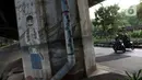 Pengendara motor melintasi sisi tiang penyangga Jalan Tol Pelabuhan Lingkar Dalam Jakarta di Jalan Ancol Timur, Jakarta, Selasa (16/6/2020). Seni mural yang dulu menghiasi tiang-tiang jalan tol di kawasan tersebut kini terlihat kusam dan berdebu. (Liputan6.com/Helmi Fithriansyah)