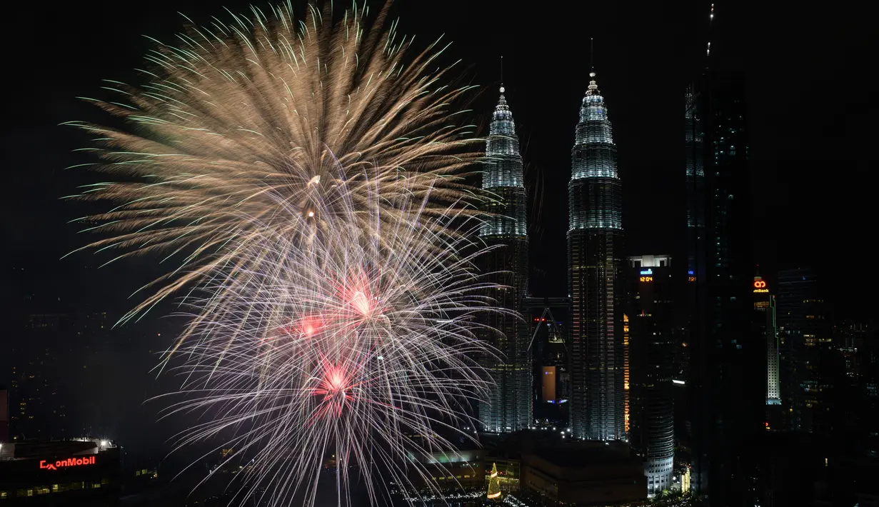 Kembang api menghiasi langit di dekat Menara Kembar Petronas Malaysia saat malam pergantian tahun di Kuala Lumpur, Malaysia. (01/1/2018). Menara Kembar Petronas menjadi salah satu spot para wisatawan menikmati malam tahun baru. (AFP Photo / Mohd Rasfan)