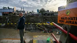 Salah satu sisi jembatan Kuta Blang runtuh akibat banjir bandang yang menerjang wilayah tersebut pada Kamis 27 November 2025 sore hari. Tampak dalam foto, seorang pria menyaksikan dari jembatan yang runtuh di atas Sungai Peusangan di Kuta Blang, Kabupaten Bireuen, Provinsi Aceh, Selasa 9 Desember 2025. (CHAIDEER MAHYUDDIN/AFP)