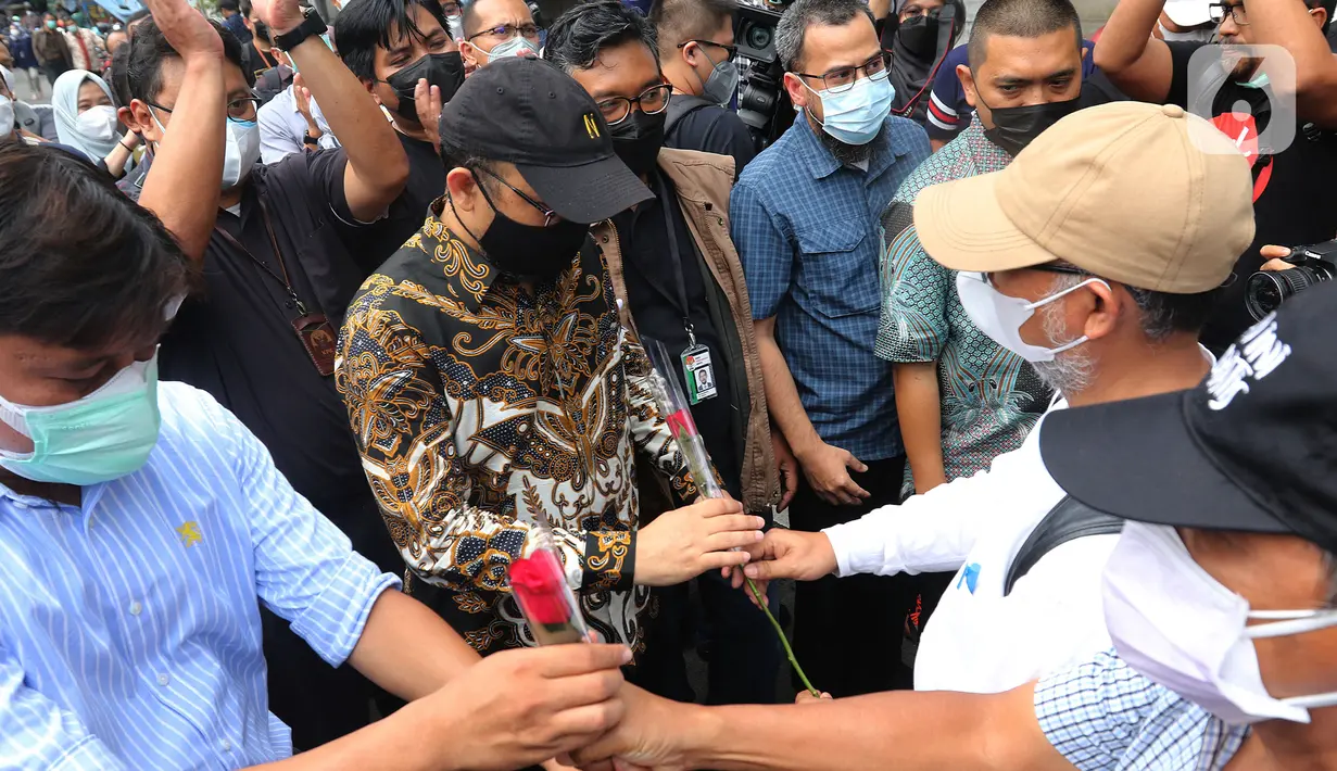 Mantan wakil ketua KPK Bambang Widjojanto memberikan bunga ke Novel Baswedan di luar Gedung KPK, Jakarta, Kamis (30/9/2021). 57 + 1 pegawai KPK yang tak lolos TWK untuk alih status ASN diberhentikan dengan hormat per 30 September 2021. (Liputan6.com/Herman Zakharia)