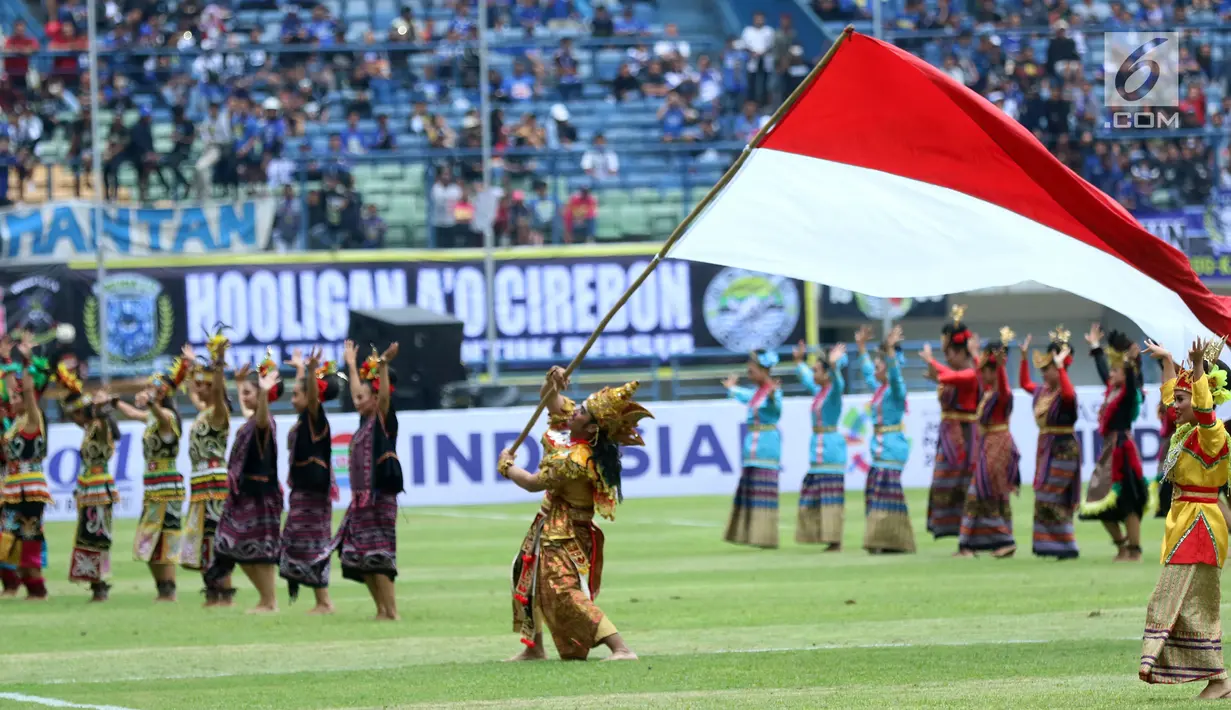 Penari mengibarkan bendera Merah Putih saat jeda laga pembuka turnamen Piala Presiden 2018 antara Persib melawan Sriwijaya FC di Stadion GBLA, Bandung, Selasa (16/1). Laga dimenangkan Persib 1-0. (Liputan6.com/Helmi Fithriansyah)