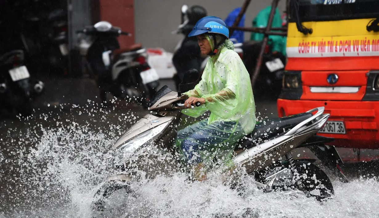 Pengendara motor melintasi banjir usai badai tropis Talas terjadi di Hanoi, Vietnam utara (17/7). Menurut Direktur Pusat Peramalan Nasional Hidro-Meteorologi Badai Talas diprediksi akan melanda provinsi-provinsi utama Vietnam. (AFP Photo/Hoang Dinh Nam)
