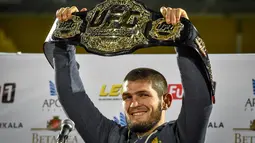 Juara kelas ringan UFC, Khabib Nurmagomedov mengangkat sabuk juaranya saat tiba di Makhachkala, Rusia, Senin (8/10). Khabib menjadi pusat perhatian dunia setelah sukses mempertahankan sabuk juara kelas ringan melawan Conor McGregor. (AFP/Vasily MAXIMOV)