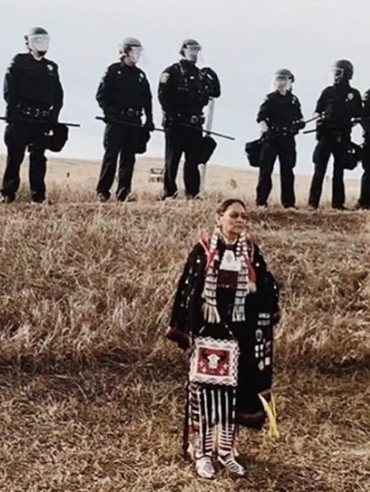 Foto yang diunggah Katy merupakan sosok wanita asli Amerika yang sedang berdiri di depan barisan polisi yang hendak melakukan perlawanan. (Instagram/Katyperrie)