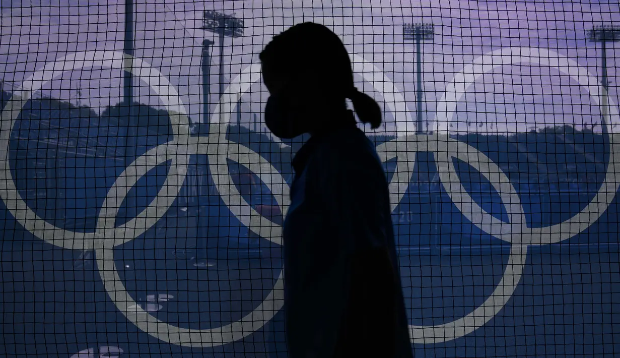Seorang petugas lapangan melewati jaring yang dihiasi dengan Cincin Olimpiade di lapangan utara Stadion Hoki Oi sebelum pertandingan hoki lapangan wanita antara Argentina dan Jerman di Olimpiade Musim Panas 2020 di Tokyo, Jepang, Selasa (2/8/2021). (AP Photo/John Locher)