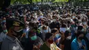 Polisi melakukan pengamanan saat warga menunggu dalam antrean untuk mendaftar vaksin virus corona COVID-19 AstraZeneca di Denpasar, Bali, Sabtu (26/6/2021). Ratusan warga terlihat antusias mengikuti vaksinasi massal ini. (SONY TUMBELAKA/AFP)