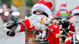 Pengendara berpakaian seperti Sinterklas mengendarai sepeda motor selama acara amal di Lustadt, Jerman, Kamis (6/12). Mereka mengumpulkan sumbangan untuk rumah sakit Sterntaler di Speyer, yang merawat anak-anak penderita kanker. (Uwe Anspach/dpa/AFP)