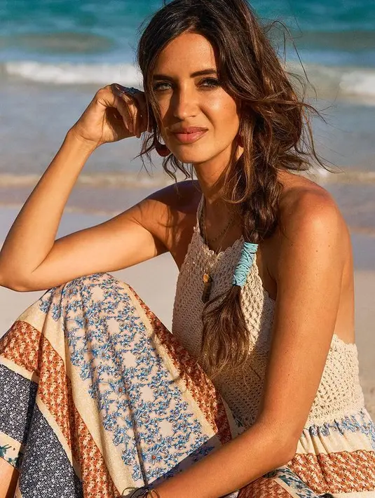 Dengan outfit yang lebih simple, Sara mengenakan halterneck dress yang memadukan dua bahan. Atasan rajut berwarna putih dipadukan dengan rok bermotif yang stylish. (instagram/saracarbonero)