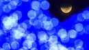 Terlihat melewati lampu Natal, bayangan bumi mulai menutupi bulan saat gerhana bulan, di alun-alun di Caracas, Venezuela, Selasa dini hari, 8 November 2022. Fenomena gerhana bulan total terjadi pada 8 November 2022 di berbagai negara. (AP Photo/Matias Delacroix)