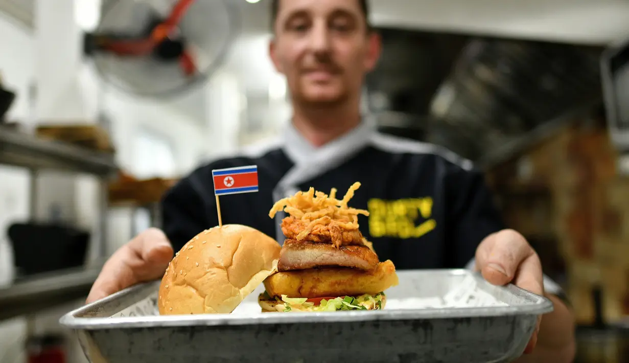 Koki Irlandia, Colin Kelly berpose dengan burger "Kim Jong Yum" di restoran Durty Bird, Hanoi, Vietnam, 21 Februari 2019. Menu baru ini terinspirasi pertemuan puncak antara Presiden AS Donald Trump dan pemimpin Korut, Kim Jong-un. (Manan VATSYAYANA/AFP)