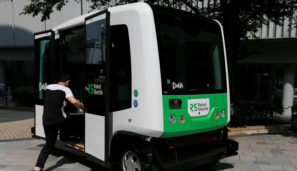 Seorang lelaki memasuki Robot Shuttle saat didemonstrasikan di Tokyo, Jepang, Kamis (7/7). Robot Shuttle adalah bus kemudi otomatis sehingga tak membutuhkan sopir untuk pengoperasiannya. (REUTERS / Toru Hanai)