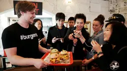 Pengunjung memfoto burger berkarakter pokemon di restoran Down N 'Out Burger, Sydney, Australia, (26/8). Restoran ini menyebut burger kreasi mereka dengan sebutan "Pokeburg". (REUTERS/Jason Reed)