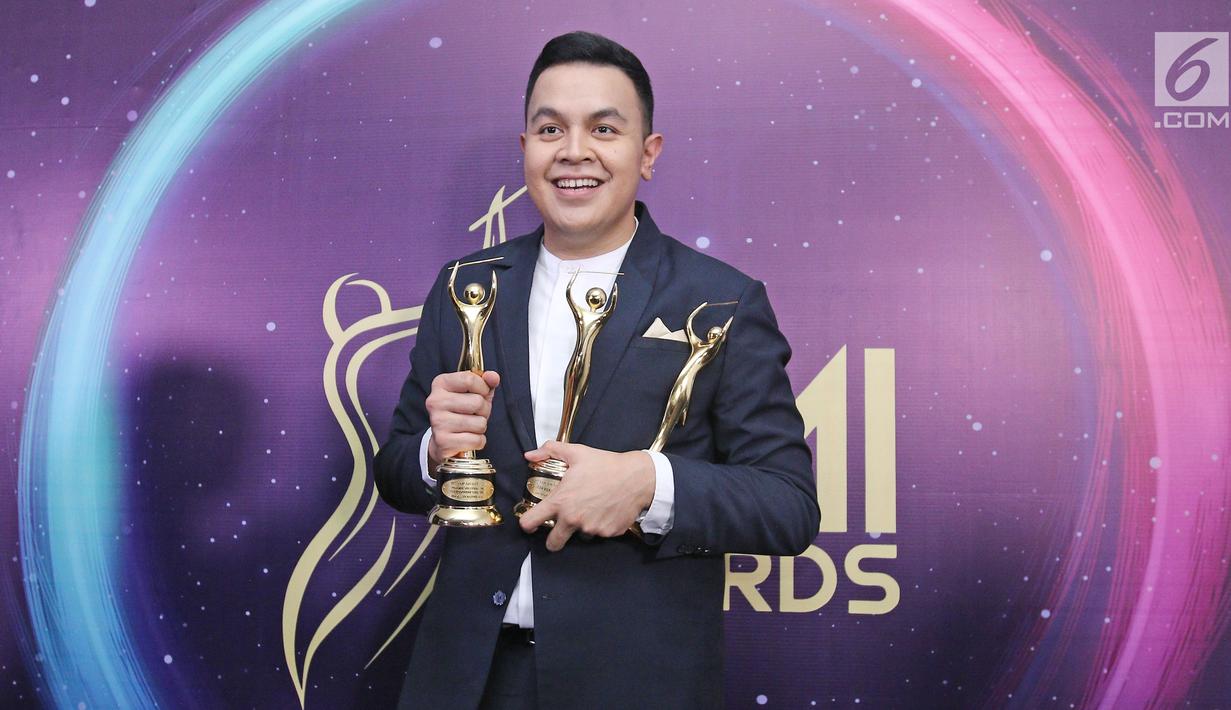 Penyanyi Tulus berpose memenggang piala usai meraih penghargaan Anugerah Musik Indonesia (AMI) Awards 2017 di Teater Garuda TMII, Jakarta, Kamis (16/11). Tulus berhasil membawa pulang empat piala. (Liputan6.com/Herman Zakharia)