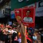 Seorang pengunjuk rasa memegang poster dengan gambar pemimpin terpilih Aung San Suu Kyi (kanan) yang ditahan dan presiden Win Myint saat demonstrasi menentang kudeta militer di Yangon, Myanmar pada Sabtu (6/2/2021).  Ribuan orang turun ke jalan-jalan untuk melawan kudeta. (YE AUNG THU / AFP)