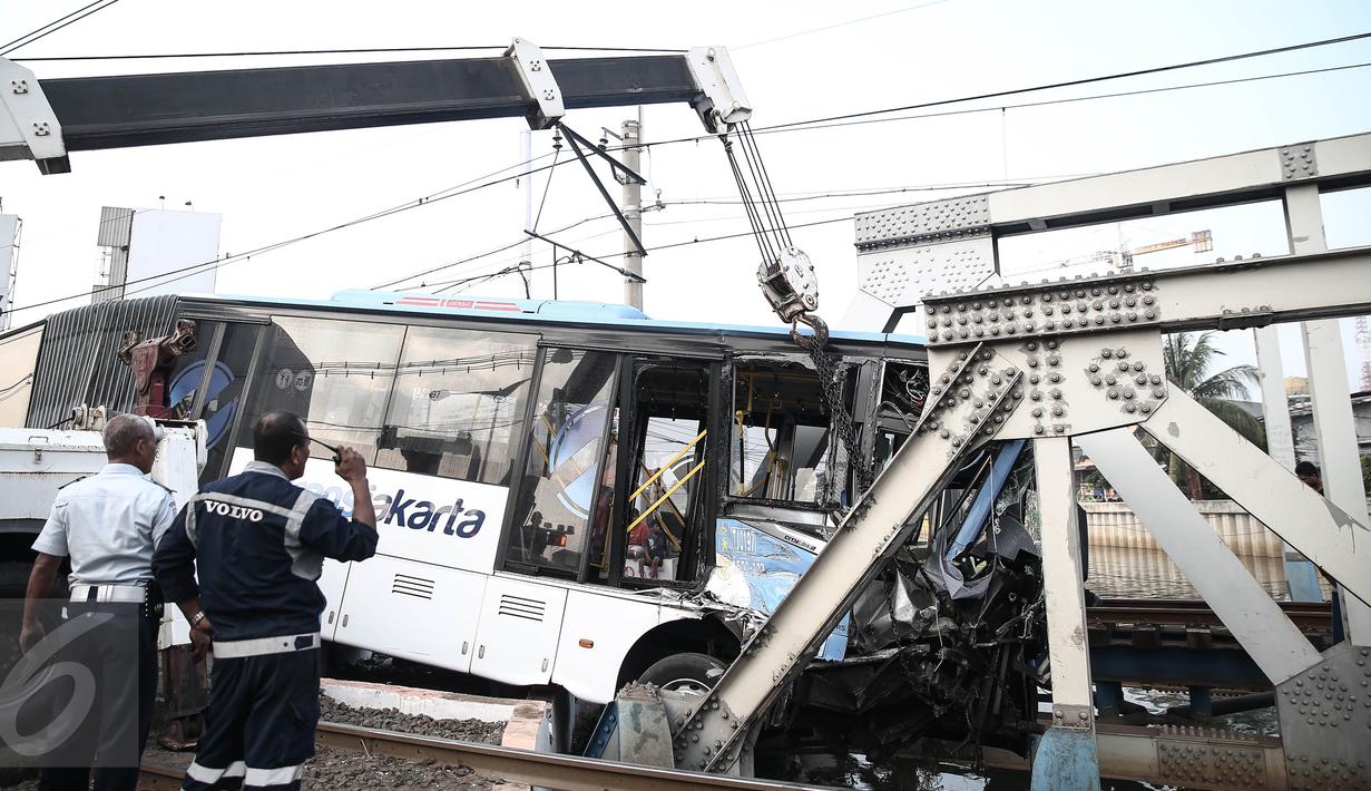 Petugas mengamati evakuasi bus transjakarta usai ditabrak kereta Senja Utama Solo di perlintasan Jalan Mangga Dua, Jakarta, Kamis (19/5). Menurut keterangan, insiden itu disebabkan bus Transjakarta yang menerobos palang pintu. (Liputan6.com/Faizal Fanani)