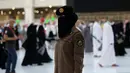 Seorang polisi wanita Saudi berjaga-jaga saat jemaah mengelilingi Ka'bah pada rangkaian ibadah haji di Masjidil Haram, Makkah, Selasa (20/7/2021). Kini, para personel perempuan bergabung dengan rekan-rekan pria mereka dalam menjaga kota suci selama musim haji. (Fayez Nureldine / AFP)