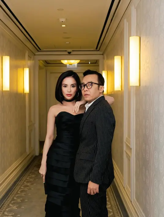 Dalam foto yang diunggah, keduanya tampil begitu serasi dalam balutan busana serba hitam yang elegan. Ari Lasso tampil sleek dengan setelan pinstripe hitam-putih yang memberi sentuhan klasik sekaligus edgy. Gaya rambut klimis dan sepatu kulit hitam menyempurnakan penampilannya yang formal tapi tetap penuh gaya.  [@ari_lasso].
