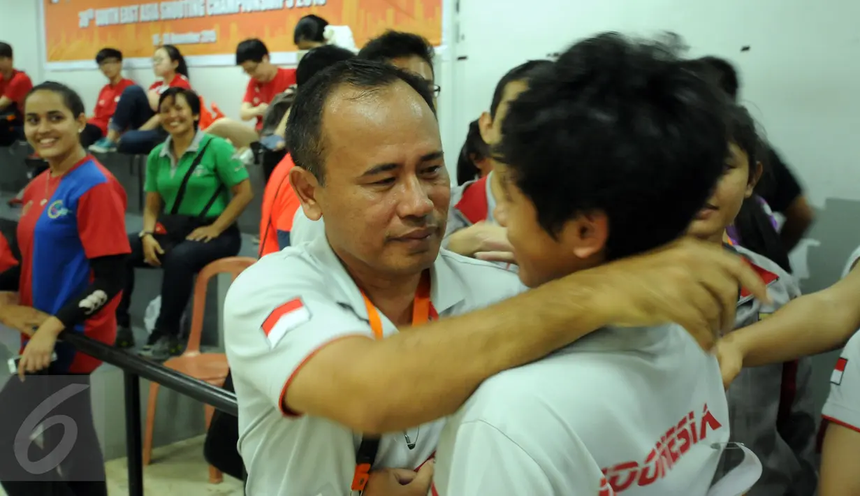 Petembak Junior Indonesia, I Kadek Rico V (kanan) dipeluk pelatihnya, I Made Sugiantara usai memastikan meraih emas 10m Air Pistol Men Junior Kejuaraan Menembak ASEAN di Jakarta, Rabu (25/11/2015). (Liputan6.com/Helmi Fithriansyah)