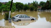 Sebuah mobil terlihat sebagian terendam banjir di daerah pemukiman, Batu Berendam, Malaka, Malaysia, 3 Januari 2022. Setidaknya ada 50 orang tewas dalam banjir di Malaysia. (NAZRULHAD HASHIM/AFP)