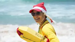 Seorang penyelamat mengenakan topi Santa sambil mengawasi orang-orang yang berkumpul di Pantai Bondi untuk merayakan Natal di Sydney, Sabtu