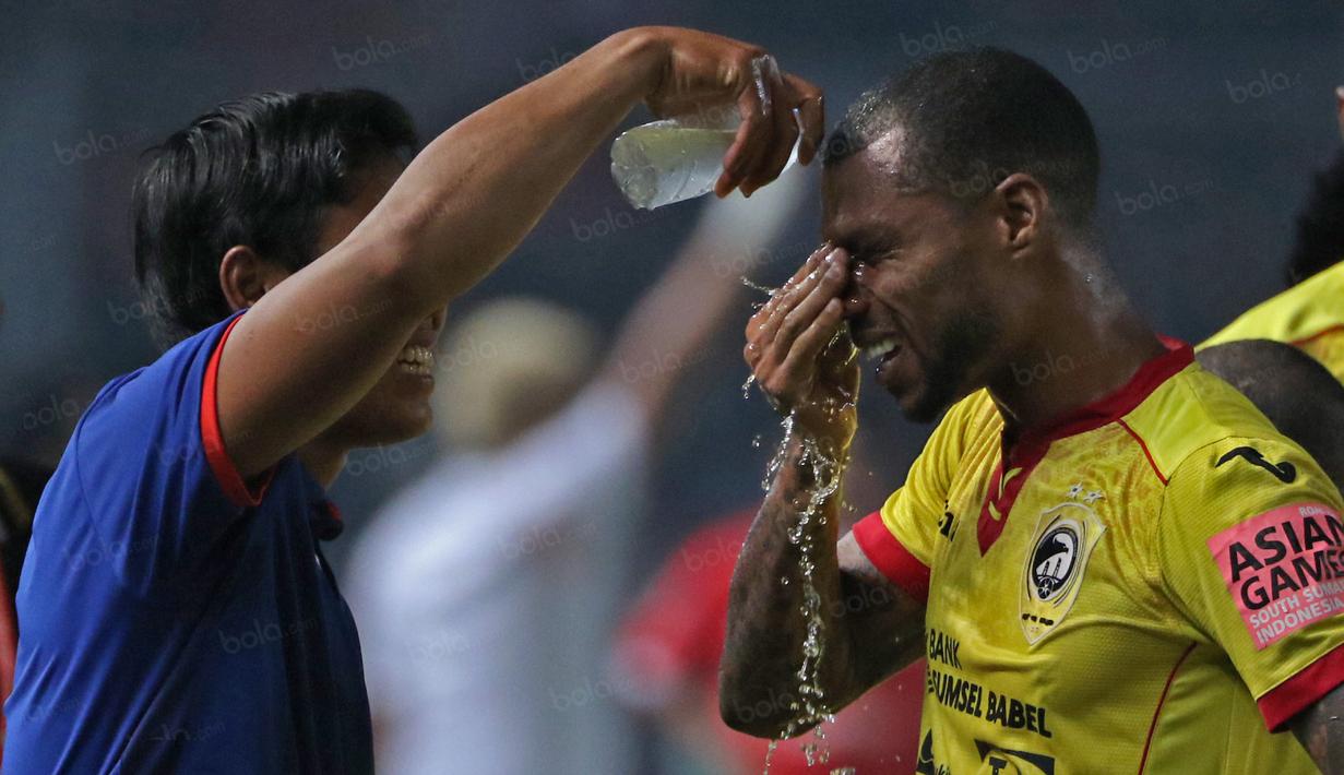 Pemain Sriwijaya FC, Hilton Moreira mebasuh wajahnya dari asap gas airmata pada laga Torabika SC 2016 antara Persija Jakarta vs Sriwijaya FC di  Stadion Utama Gelora Bung Karno (24/6/2016).  (Bola.com/Nicklas Hanoatubun)