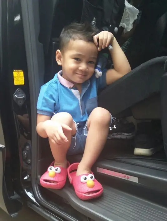 Tingkah lucu Rafathar kali ini adalah begitu santainya ia duduk di pinggir pintu mobil orang tuanya. Berpenampilan santai dengan sandal lucunya, Rafathar berpose di kamera juga memamerkan senyuman tampannya. (Instagram/raffinagita1717)