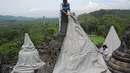 Pekerja menutup stupa di kompleks candi Borobudur, Magelang, Jawa Tengah, Senin (23/11/2020). Penutupan candi Borobudur oleh BKB (Balai Konservasi Borobudur) sebagai langkah antisipasi melindungi batu candi dari abu vulkanik jika Gunung Merapi erupsi. (Photo by Agung Supriyanto/AFP)