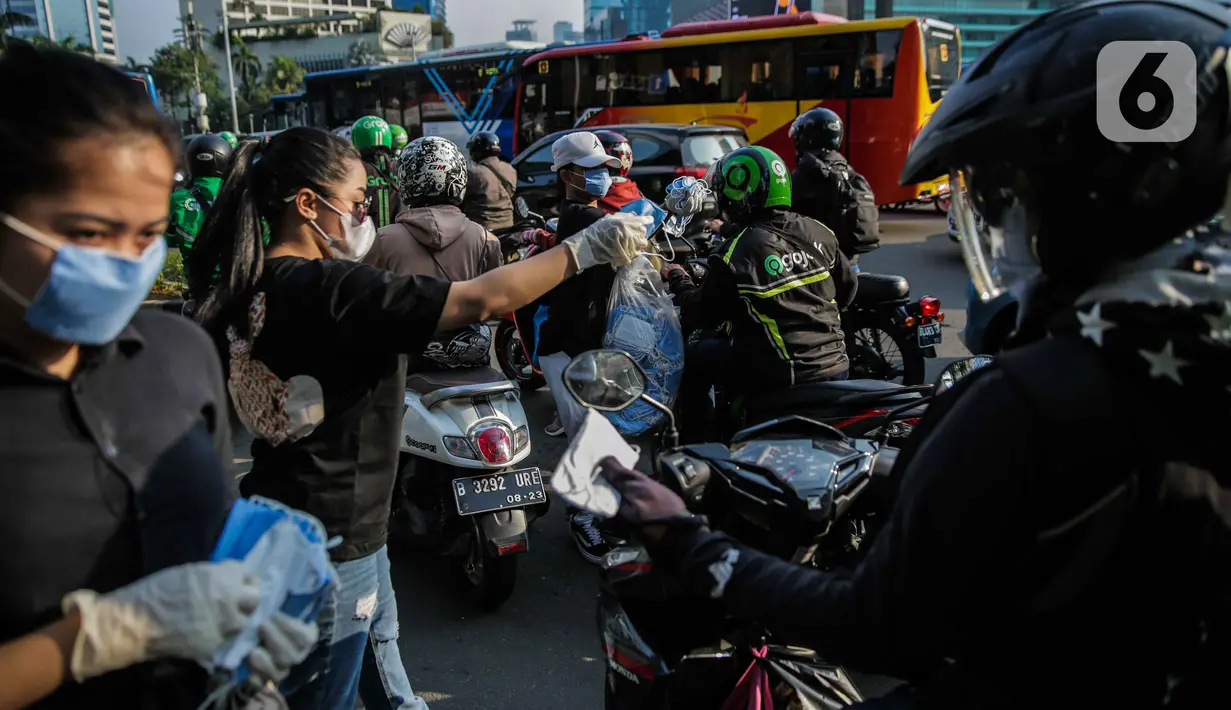 Relawan membagikan masker kepada pengguna jalan di Kawasan Bundaran HI, Jakarta, Selasa (17/3/2020). Sebanyak 3.000 masker dibagikan secara gratis sebagai salah satu bentuk keprihatinan sekaligus berpartisipasi dalam upaya mencegah penyebaran virus corona COVID-19. (Liputan6.com/Faizal Fanani)