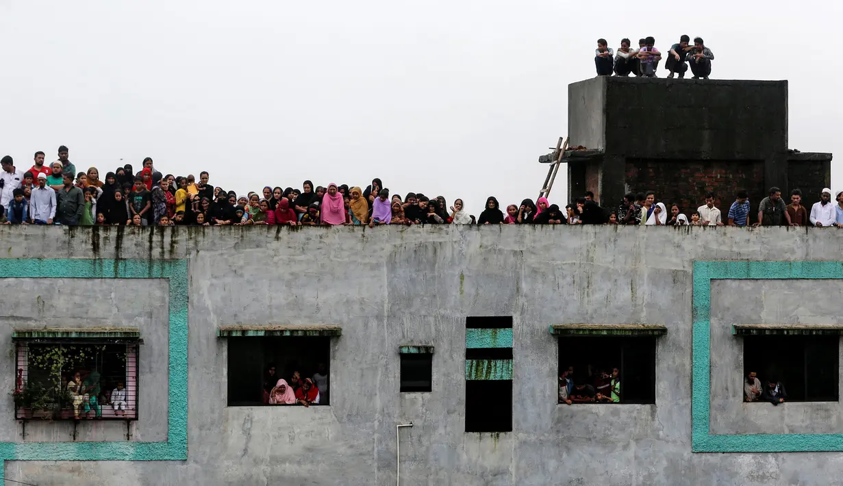 Warga berkumpul melihat proses evakuasi di lokasi ambruknya bangunan perumahan di pinggiran Mumbai, India, Minggu (31/7). Akibat hujan lebat, bangunan perumahan ambruk dan menewaskan 9 orang termasuk empat anak-anak. (REUTERS/Shailesh Andrade)
