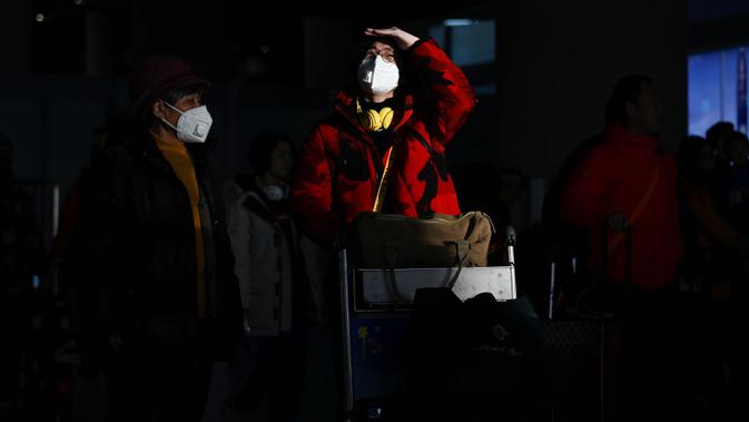 Dua penumpang yang mengenakan masker tiba di Bandara Internasional Beijing pada 20 Januari 2020,menjelang Tahun Baru Imlek. China berada di tengah-tengah kesibukan migrasi manusia tahunan ketika jutaan orang pulang ke kampung halaman mereka untuk menikmati libur Tahun Baru Imlek. (WANG Zhao/AFP)