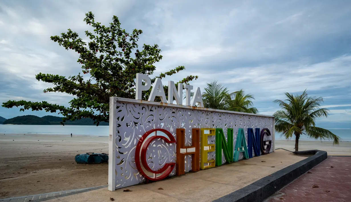 Papan nama Pantai Cenang, tujuan wisata populer di pulau liburan Langkawi, yang ditutup untuk sebagian besar pengunjung luar karena penguncian sebagian yang ditetapkan pihak berwenang untuk mengekang penyebaran Covid-19, di Kedah, Malaysia utara (18/11/2020). (AFP/Mohd Rasfan)