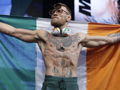 Conor McGregor membentangkan bendera Irlandia saat timbang badan jelang melawan Floyd Mayweather di Las Vegas (25/8/2017). McGregor akan bertarung 26 agustus 2017. (AP/John Locher)