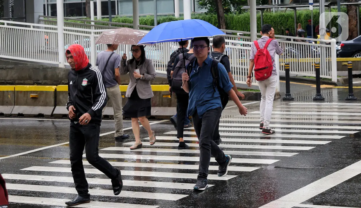 Pejalan kaki melintas menggunakan payung saat hujan mengguyur kawasan Jakarta, Senin (3/2/2020). Diperkirakan sejumlah wilayah berpotensi diguyur hujan dengan intensitas lebat hingga disertai dengan angin kencang, kilat/petir hingga Rabu (5/2/2020) mendatang. (Liputan6.com/Angga Yuniar)