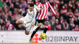 Pemain Real Madrid, Kylian Mbappe (kiri) berebut bola dengan pemain Athletic Bilbao, Adama Boiro dalam laga lanjutan Liga Spanyol 2025/2026 di Stadion San Mames, Bilbao, Spanyol, Rabu (03/12/2025). (AP Photo/Jose Breton)