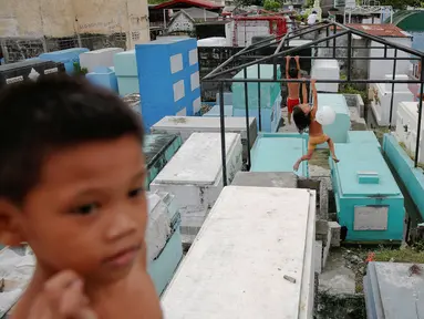 Anak-anak bermain di kuburan bergaya apartemen yang dibangun di North Cemetery, Manila, Filipina, (16/10). Kuburan ini tidak hanya menjadi tempat pemakaman orang mati, tapi juga ditinggali oleh warga yang tidak mampu membeli rumah. (Reuters/ Damir Sagolj)