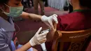 Seorang petugas kesehatan disuntik vaksin COVID-19 CoronaVac dari Sinovac, di Institut Penyakit Menular Bamrasnaradura di Bangkok, Minggu (28/2/2021). Pekan ini, Thailand menerima 200.000 dosis pertama vaksin Sinovac dari China dan 117.00 dosis impor vaksin AstraZeneca. (Lillian SUWANRUMPHA/AFP)