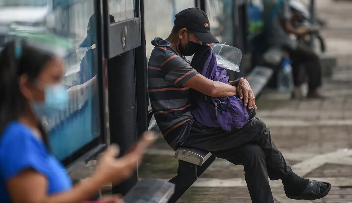 Seorang pria beristirahat sambil menunggu angkutan kota jeepney di Manila, sehari sebelum pihak berwenang mencabut perintah tinggal di rumah pada Selasa (7/9/2021). Filipina akan mencabut lockdown di ibu kota Manila pada Rabu (8/9), saat kasus corona harian naik dua kali lipat. (Ted ALJIBE/AFP)