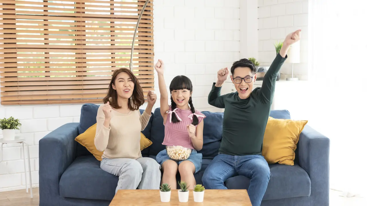 Sebuah keluarga kecil sedang bersorak gembira di ruang keluarga (Foto Dok: Freepik/our-team)