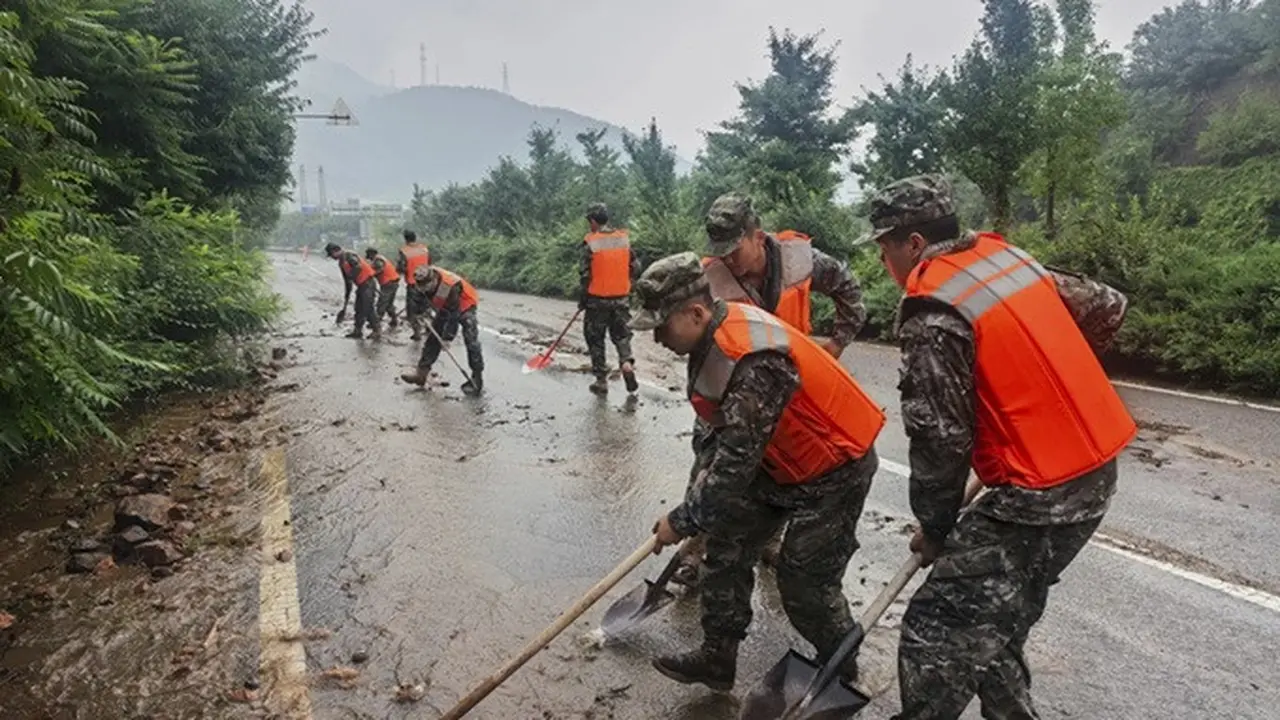 Dalam foto yang dirilis oleh Kantor Berita Xinhua, Polisi Bersenjata Rakyat China membersihkan lumpur di sebuah jalan di Distrik Miyun, Beijing, pada Minggu (27/7/2025).