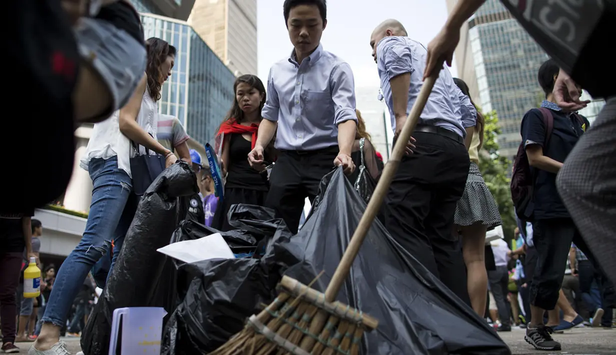 Beberapa pekerja kantor membersihkan lokasi terjadinya bentrok massa pro-demokrasi dan anti-demokrasi di daerah pusat bisnis Hong Kong, (13/10/2014). (REUTERS/Tyrone Siu)