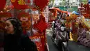 Pengendara memegang ponsel melewati sebuah pasar yang menjual dekorasi Tahun Baru Imlek atau perayaan Tet di pusat Kota Tua Hanoi, Senin (28/1). Di Vietnam, tahun baru imlek dikenal dengan nama Tet Nguyen Dan atau disingkat Tet. (Manan VATSYAYANA/AFP)