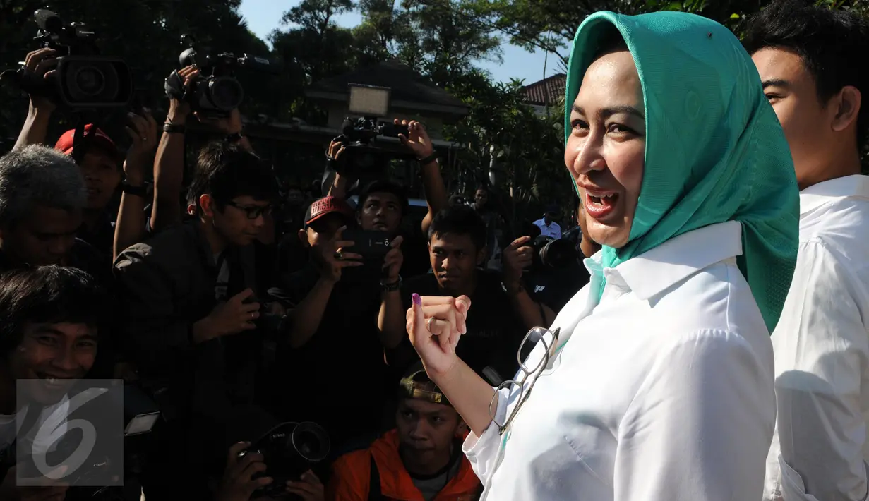 Calon Walikota Tangerang Selatan, Airin Rachmi Diany bersama putra pertama, TB Ghifari Wardana menunjukkan jarinya usai menggunakan hak pilih di TPS 17 Serpong Utara, Tangerang Selatan, Banten, Rabu (9/12). (Liputan6.com/Helmi Afandi)