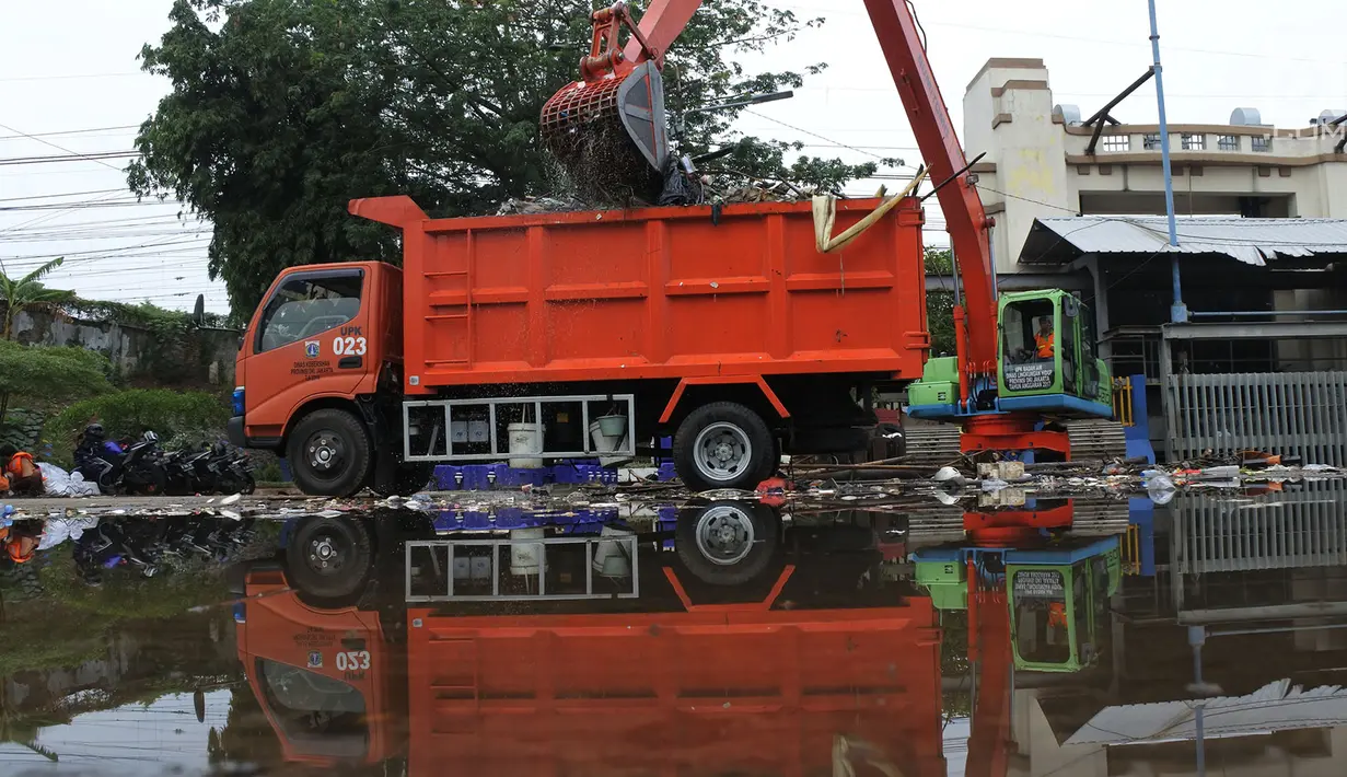Petugas mengangkut sampah yang terbawa arus sungai Ciliwung ke dalam truk, Jakarta, Selasa (23/10). Dinas Lingkungan Hidup mengantisipasi terjadinya peningkatan volume sampah saat musim penghujan tiba di setiap pintu air Jakarta. (Merdeka.com/Imam Buhori)