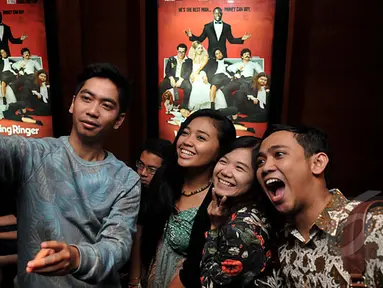 Sambil menunggu studio dibuka, penonton ini asyik selfie di depan poster film  saat Premier Film The Wedding Ringer, Jakarta, Selasa,(17/2/2015) (Liputan6.com/Johan Tallo)