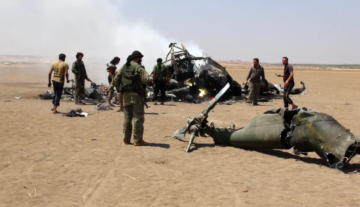 Pemberontak Suriah memeriksa reruntuhan helikopter milik Rusia yang ditembak jatuh di wilayah Idlib, Suriah, Senin (1/8). Helikopter berjenis Mi-8 itu membawa tiga kru dan dua petugas yang diperkirakan tewas. (Mohamed al - Bakour/AFP)