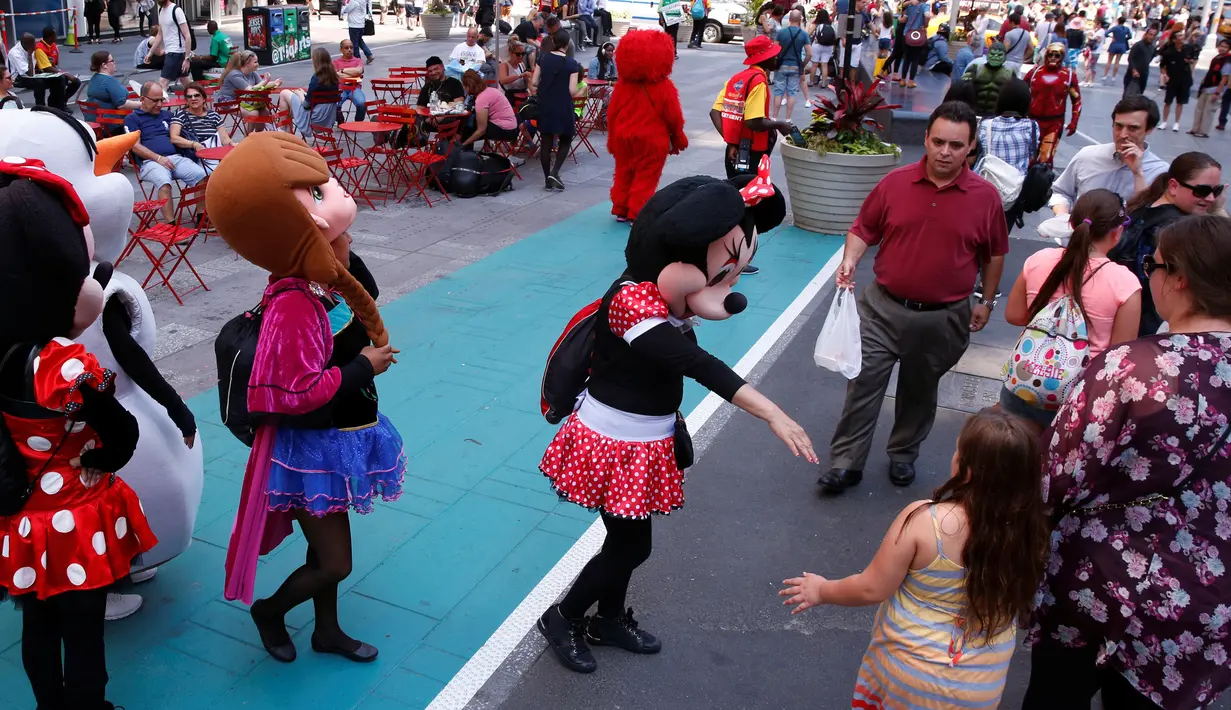 Karakter Disney Minnie Mouse menawarkan pengunjung untuk berfoto bersama di Times Square, New York, Selasa (21/6). Di sini banyak terdapat beraneka macam pengamen jalanan untuk menghibur pengunjung. (REUTERS/Lucas Jackson)