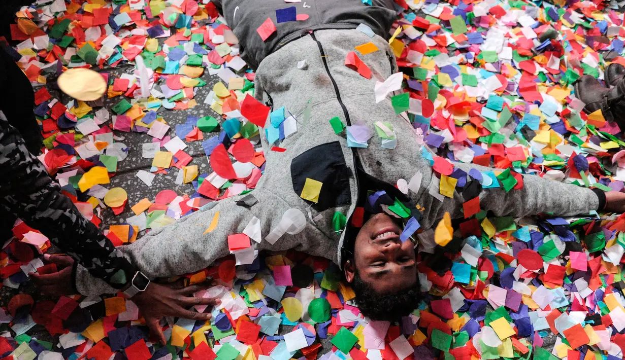 Seorang pria berbaring diantara confetti saat perayaan tahun baru di Times Square, New York, AS (1/1). Pesta pergantian tahun di New York dipusatkan di Times Square, ribuan orang membanjiri tempat tersebut untuk merayakannya. (Reuters/Stephanie Keith)
