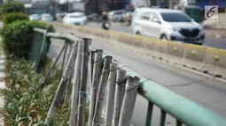 Kondisi pagar pembatas jalur transjakarta yang ditopang bambu di Jalan Otista Raya, Jakarta, Jumat (5/7/2019). Meskipun telah lama rusak, pagar besi berjeruji yang berfungsi sebagai pembatas agar orang tidak menyeberang secara sembarangan itu belum juga diperbaiki. (Liputan6.com/Immanuel Antonius)