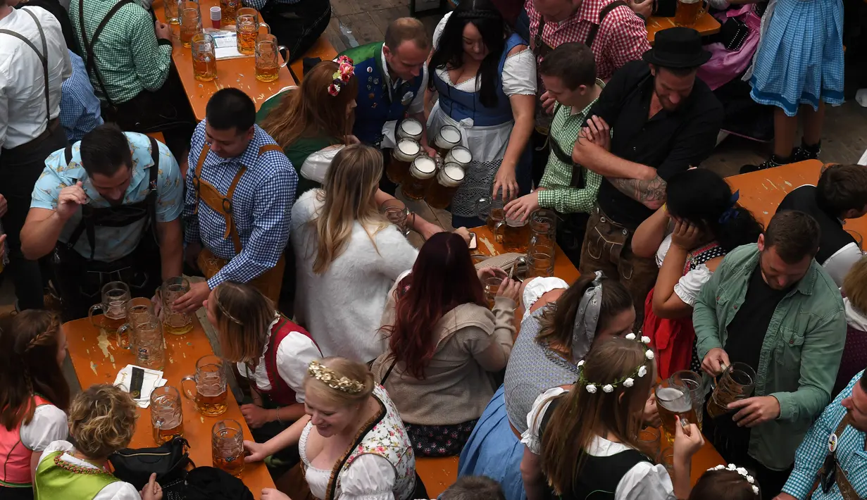 Pengunjung menikmati bir selama Festival Oktoberfest 2019 di sebuah tenda di Munich, Jerman selatan (3/10/2019). Festival bir terbesar di dunia Oktoberfest berlangsung hingga 6 Oktober 2019. (AFP Photo/Christof Stache)